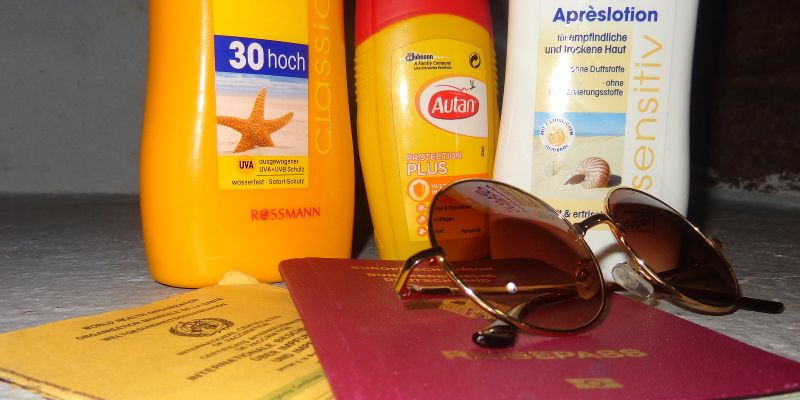 Travel preparation: Suncream, sun glasses and passport — © Laura Straub.